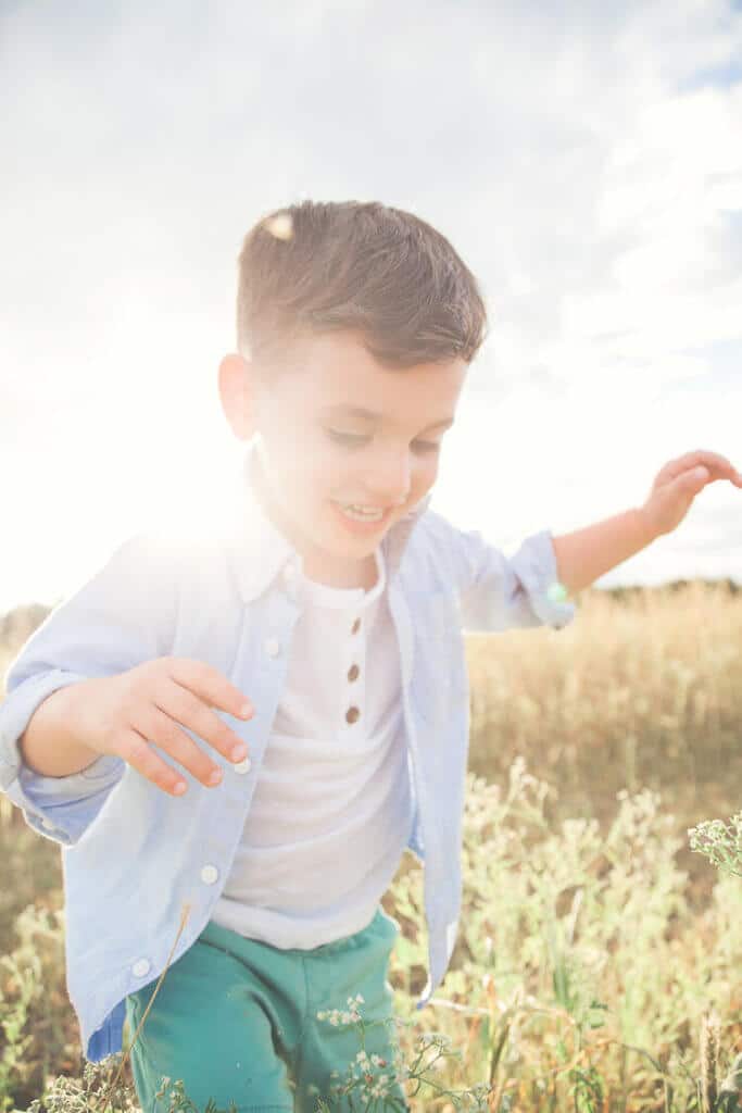 Young smiling kid being photographed while running in a family photoshoot