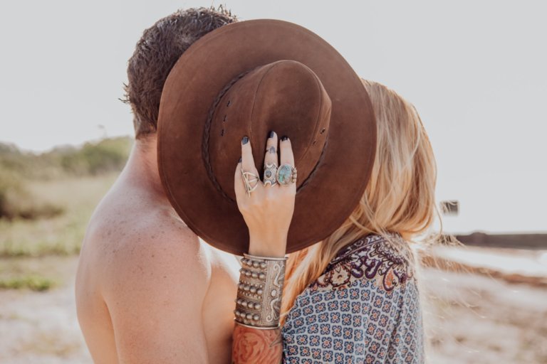 Couple kissing behind a hat