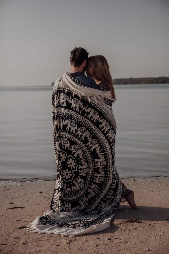 Artistic photo of couple hugging next to the sea showing their backs to the camera