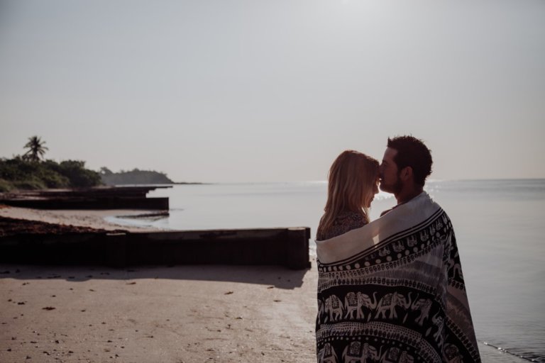 Couple hugging next to boat with soft sunlight